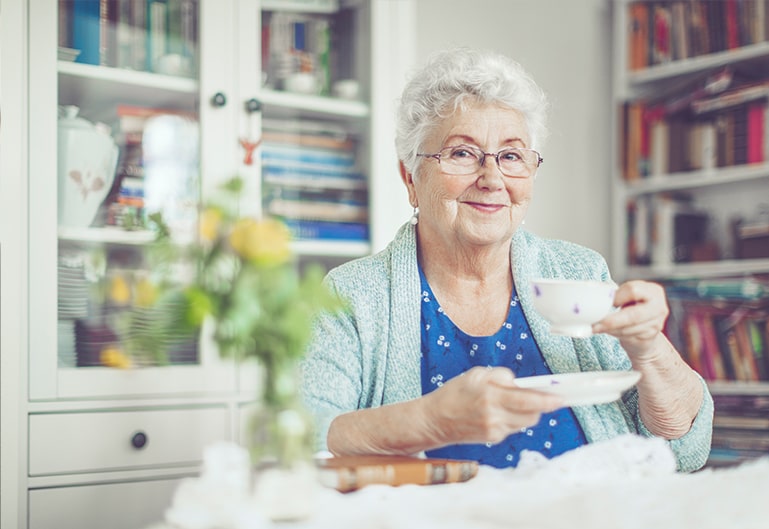 Ältere Frau trinkt zufrieden Kaffee